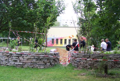 Hochbeete mit Trockenmauern aus Betonrecycling umgrenzen den Sandspielbereich